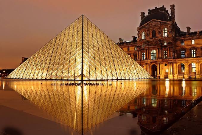 The illuminated Louvre Pyramid and museum at night